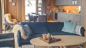 A living room with a dark blue sofa, a coffee table with a tray, and a television in the background.