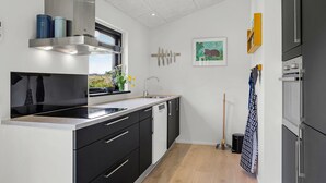 A modern kitchen with a large window, stainless steel appliances, and a minimalist design.