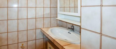 Un baño con un lavamanos blanco, un espejo encima y baldosas decorativas con motivos florales en las paredes.