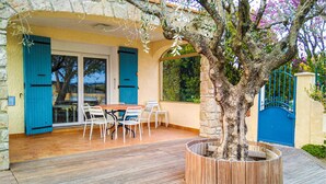 Eine Holzterrasse mit Tisch und Stühlen, einem Blumentopf mit einem Baum und einer Steinmauer.