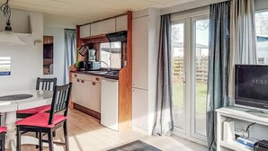 A compact kitchen with a dining area, a TV, and a view of the outdoors. - Gorgeous (sta)caravan in Tzummarum (Tzummarum)
