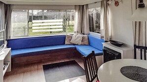 A compact living space with a blue sofa, a dining table, and a kitchen area. - Gorgeous (sta)caravan in Tzummarum (Tzummarum)