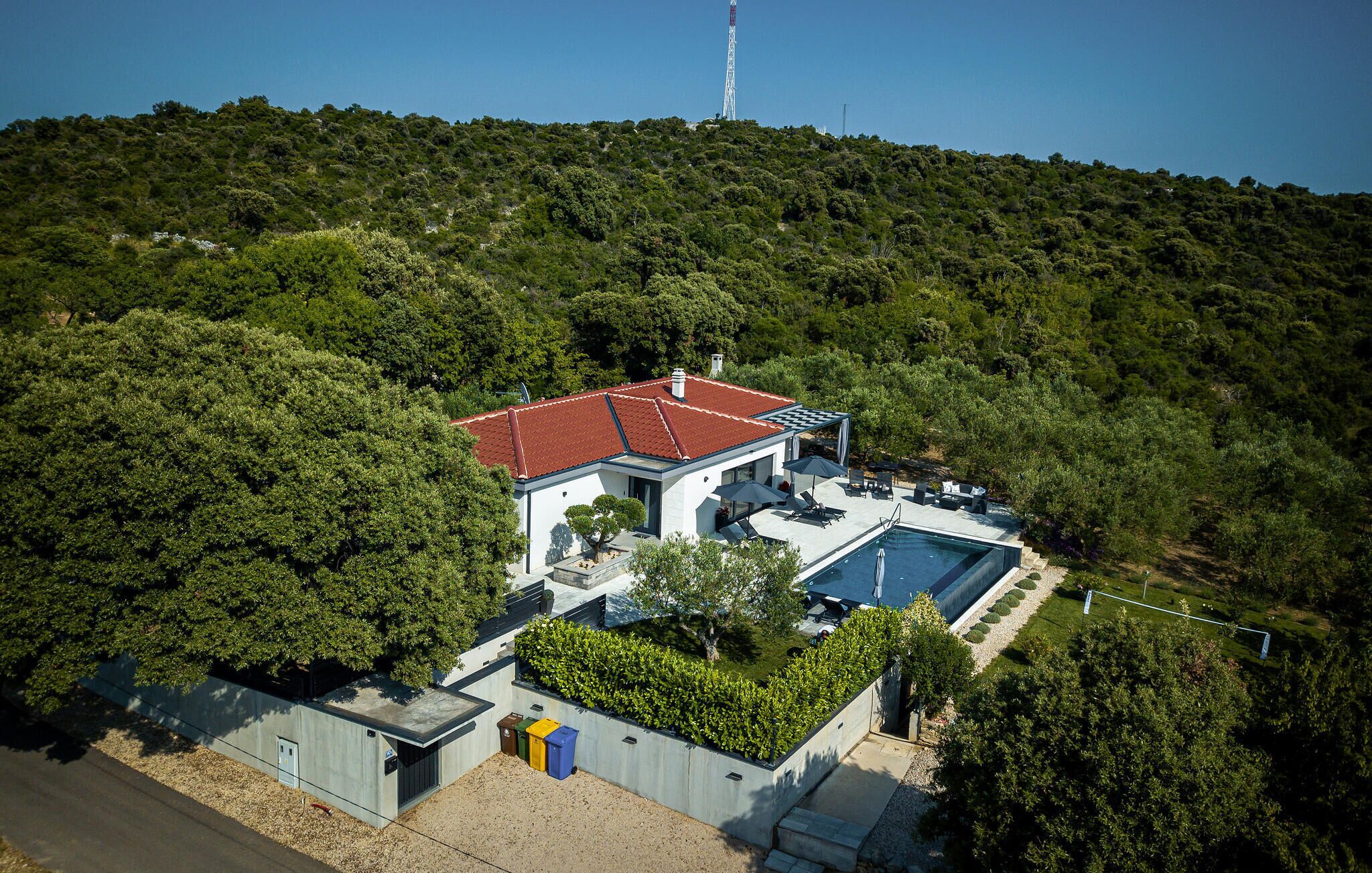 Une maison moderne dotée d’une piscine, entourée d’une végétation luxuriante et située au pied d’une colline.
