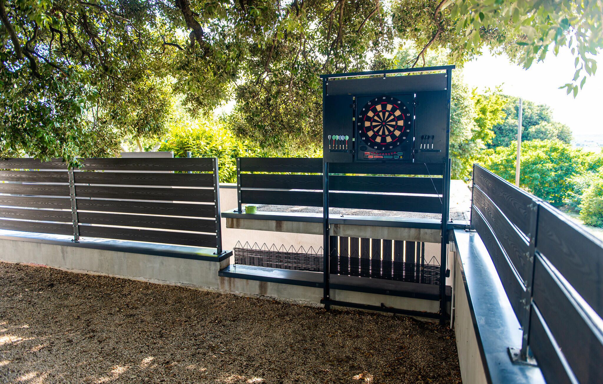 A dartboard mounted on a metal stand with a bench in the foreground.