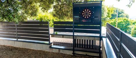 A dartboard mounted on a metal stand with a bench in the foreground.