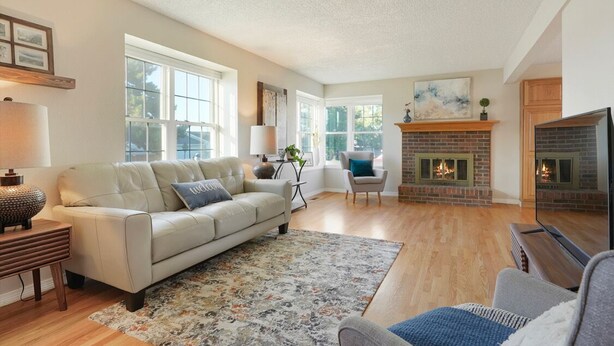 A spacious living room with a fireplace, a sofa, a coffee table, and a TV. - Cheerful 4BR House Near Red Rocks & Mountains! (Littleton)