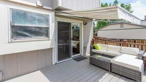 A covered patio with outdoor furniture, a sliding glass door, and a white awning. - Cheerful 4BR House Near Red Rocks & Mountains! (Littleton)
