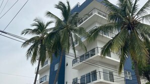 Un immeuble à plusieurs étages doté de balcons et bordé de palmiers.