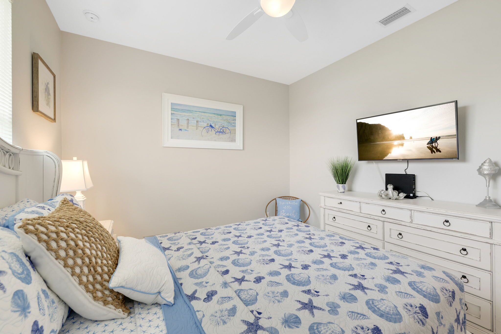 Ein Schlafzimmer mit einem Bett, einem Fernseher, einer Kommode und einem gerahmten Bild an der Wand.