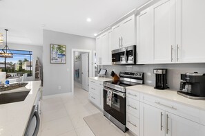 Enjoy cooking in this well-equipped kitchen with a large island, sink, and coffee machine, offering a view of the outside.