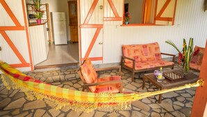 Un espacio al aire libre acogedor con una hamaca, una mesa de madera y un sofá.