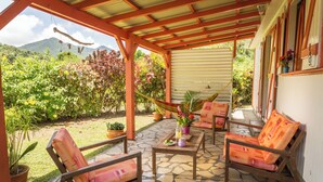 Un patio cubierto con suelo de piedra, muebles de madera y plantas en macetas.