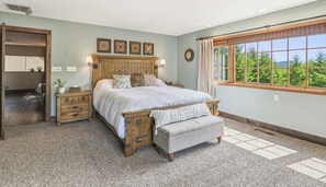 A bedroom with a wooden bed, a nightstand, a bench, and a window with a view of greenery. - The Peaceful Hidden House, Bed & Breakfast (Castle Rock)
