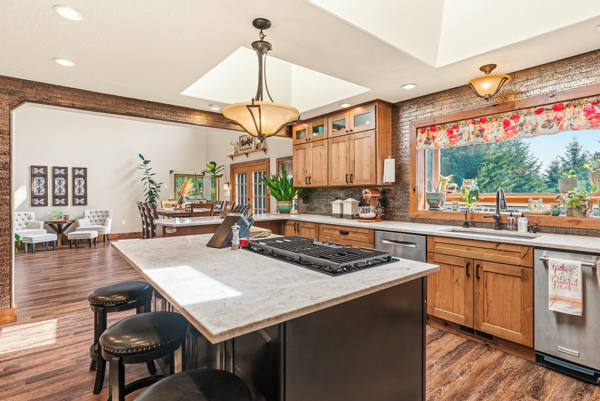 A spacious kitchen with a large island, wooden cabinets, and a view of the outdoors.