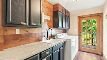 A kitchen with wooden paneling, a sink, cabinets, and a view of the outdoors through a glass door.