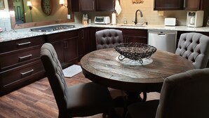 Una cocina moderna con armarios de madera oscura, una mesa redonda para comer y un original centro de mesa con un cuenco de metal.