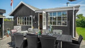 Een houten gebouw met een patio, compleet met rieten meubels en een eettafel.