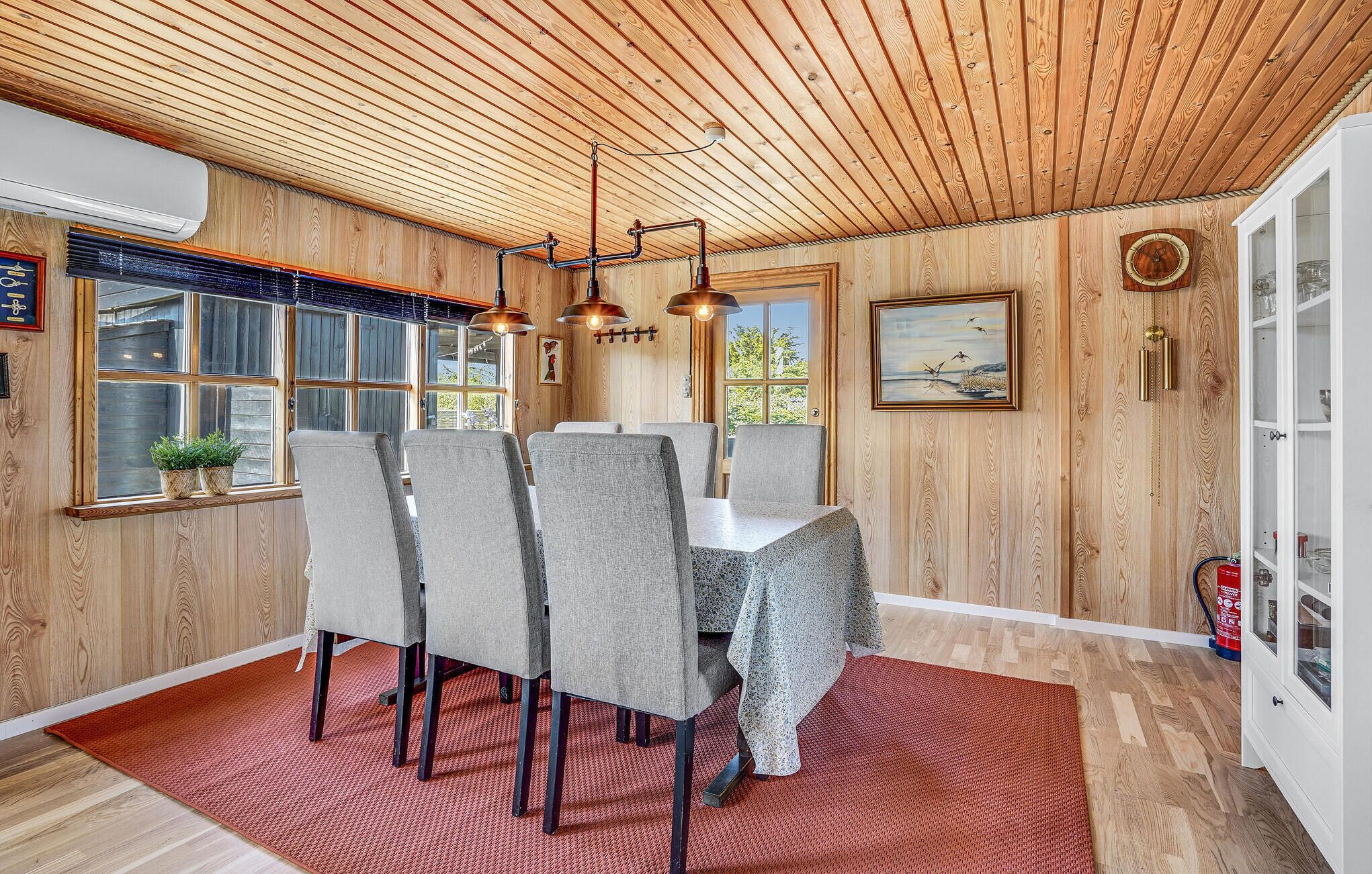 A dining area with a wooden ceiling, a large window, and a painting on the wall.