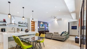 Una cocina moderna con una isla central, sillas de color verde brillante e iluminación colgante.