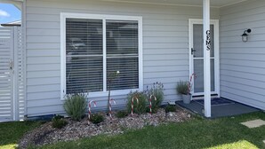 A residential house with a large window, a covered porch, and a small garden area with decorative candy canes. - Two bedroom villa with private courtyard, a short walk to Manyana Beach. (Manyana)
