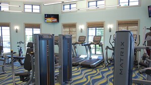 A gym with treadmills, weight machines, and a television on the wall.