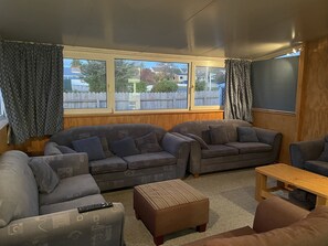 Ein Wohnzimmer mit zwei grauen Sofas, einem braunen Hocker und einem Couchtisch aus Holz.