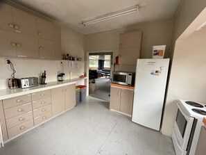 Eine Küche mit beigen Schränken, einer Mikrowelle, einem Kühlschrank und einem Herd.