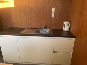 Eine Küche mit Spüle, Wasserkocher und Arbeitsplatte.