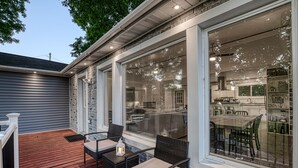 A covered outdoor patio with wicker furniture and a lantern, overlooking a brick kitchen and dining area. - Lake Escape w/ Private Dock & Spa-like amenities (Iron Mountain)