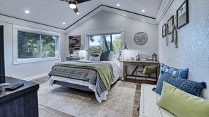 A bedroom with a large bed, a desk, and a chair. There is a window, a ceiling fan, and a wall-mounted lamp. - Lake Escape w/ Private Dock & Spa-like amenities (Iron Mountain)