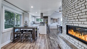 A modern kitchen with a central island, a fireplace, and large windows. - Lake Escape w/ Private Dock & Spa-like amenities (Iron Mountain)