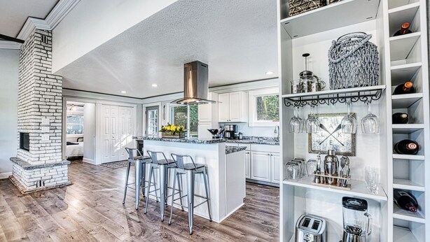 A spacious kitchen with a central island, bar stools, a brick fireplace, and a wine rack. - Lake Escape w/ Private Dock & Spa-like amenities (Iron Mountain)