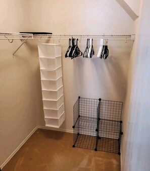 Storage area with a metal shelf unit and a white storage bin, featuring hooks for hanging items.