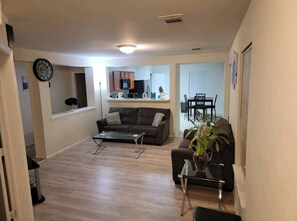 Relax in this stylish living room with a sofa, coffee table, and side table, connected to a kitchen area with a dining table.