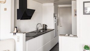 Et moderne køkken med sort emhætte, rustfrie stål-apparater og en granitbordplade.