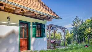 Ein rustikales Haus mit grüner Tür, einer Holzterrasse und einer Holzw pergola.