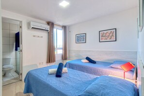 Une chambre d’hôtel avec deux lits, une salle de bain et une fenêtre avec des rideaux.