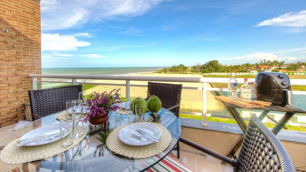 Een tafel voor twee met uitzicht op de oceaan, een bakstenen muur en een barbecue op het balkon.