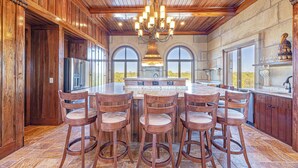A spacious kitchen with a large island, wooden ceiling, and bar stools. - Castle at Fort Morgan- Dreams do come true! (Gulf Shores)