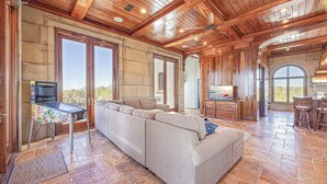 A spacious living area with a large sectional sofa, a wooden ceiling, and a stone floor. - Castle at Fort Morgan- Dreams do come true! (Gulf Shores)