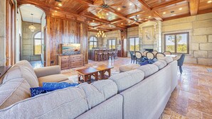 A spacious living room with a large sectional sofa, wooden ceiling beams, and a fireplace. - Castle at Fort Morgan- Dreams do come true! (Gulf Shores)
