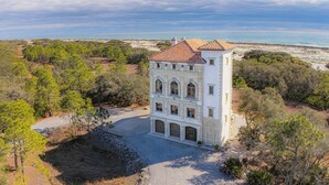 A white building with a red-tiled roof, surrounded by trees and a beach. - Castle at Fort Morgan- Dreams do come true! (Gulf Shores)