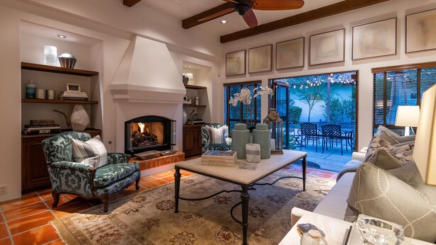 Una sala de estar acogedora con chimenea, un sillón verde, un sofá y un comedor con mesa y sillas.