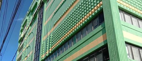 Un bâtiment vert doté de nombreuses fenêtres et d’une enseigne indiquant le « Meaco Royal Hotel ».