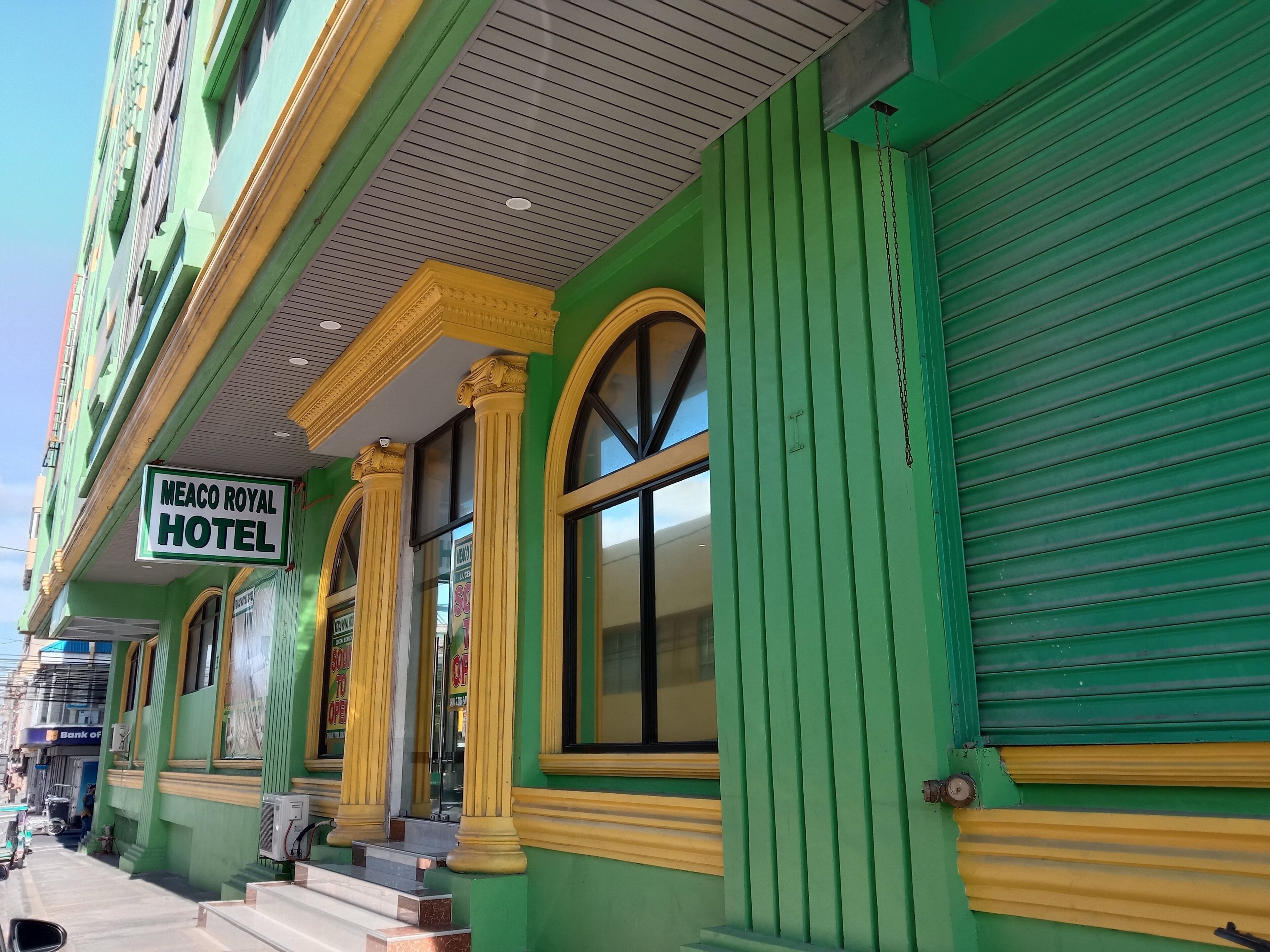 A green building with a sign reading "Meaco Royal Hotel".