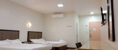 A hotel room with two beds, a desk, and a mirror.