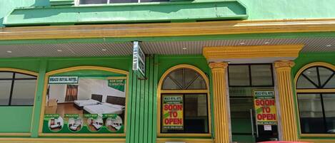 A green building with a sign indicating the Meaco Royal Hotel is now open.