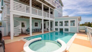 A two-story house with a swimming pool, a covered patio with outdoor furniture, and a staircase leading to the upper level. - Oceanside, ELEVATOR, Indoor-Outdoor pool, Sauna, Rec Room, Media Room, BH12, Celtic Tides (Corolla)