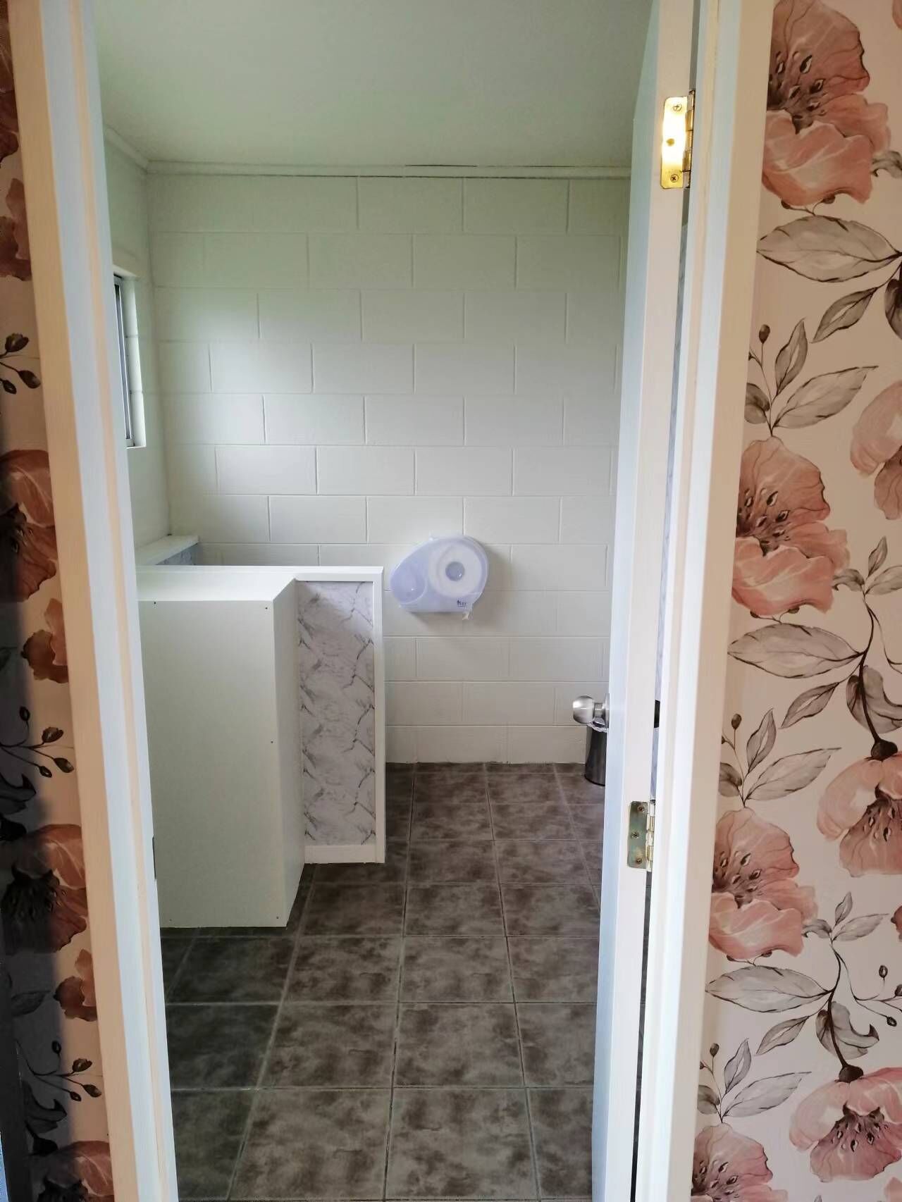 A bathroom with white tiled walls, a shower area, and a toilet.