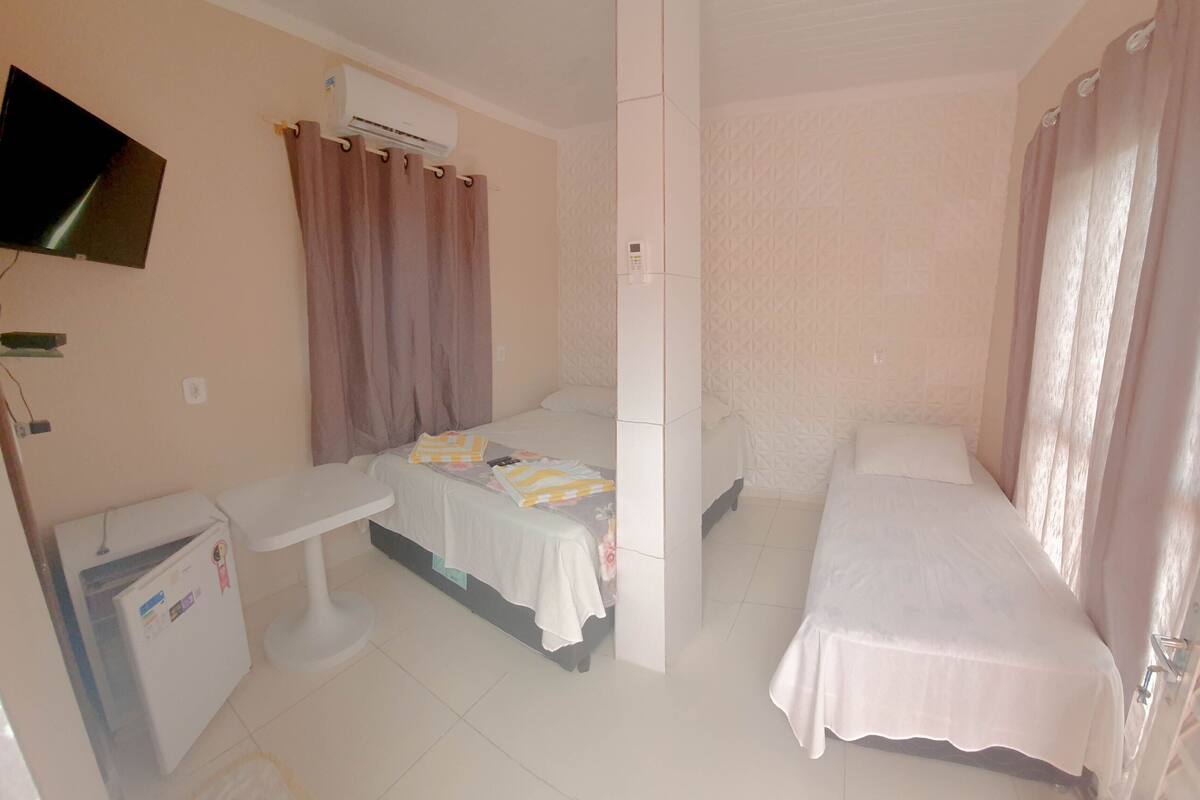 Une petite chambre propre, équipée de deux lits, d’un bureau, d’une télévision et d’un climatiseur.